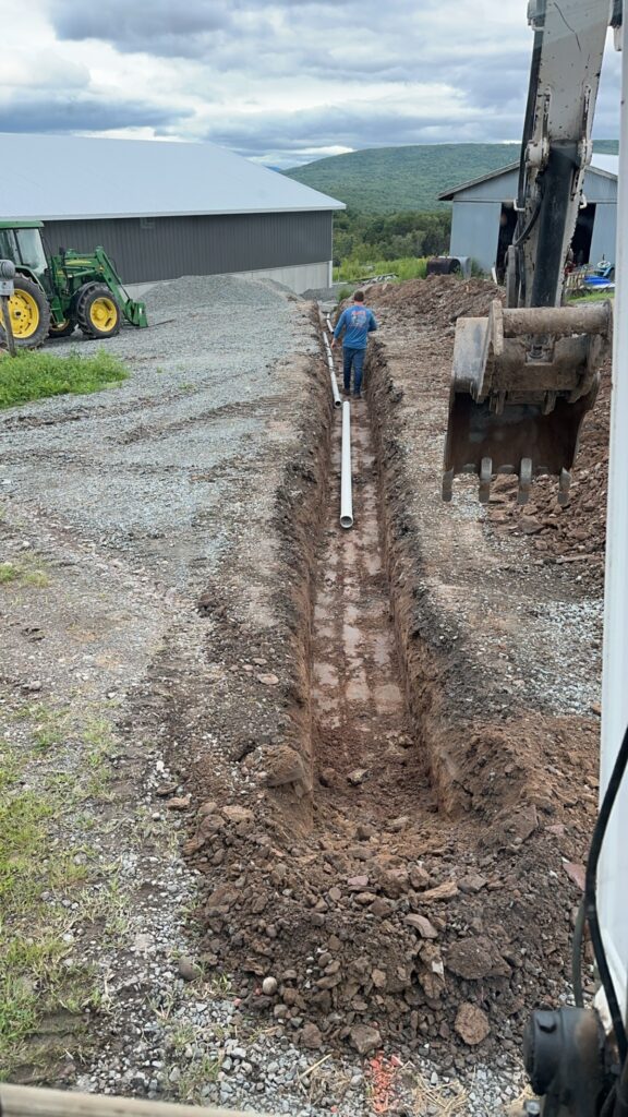 Man digging trench for pipe installation