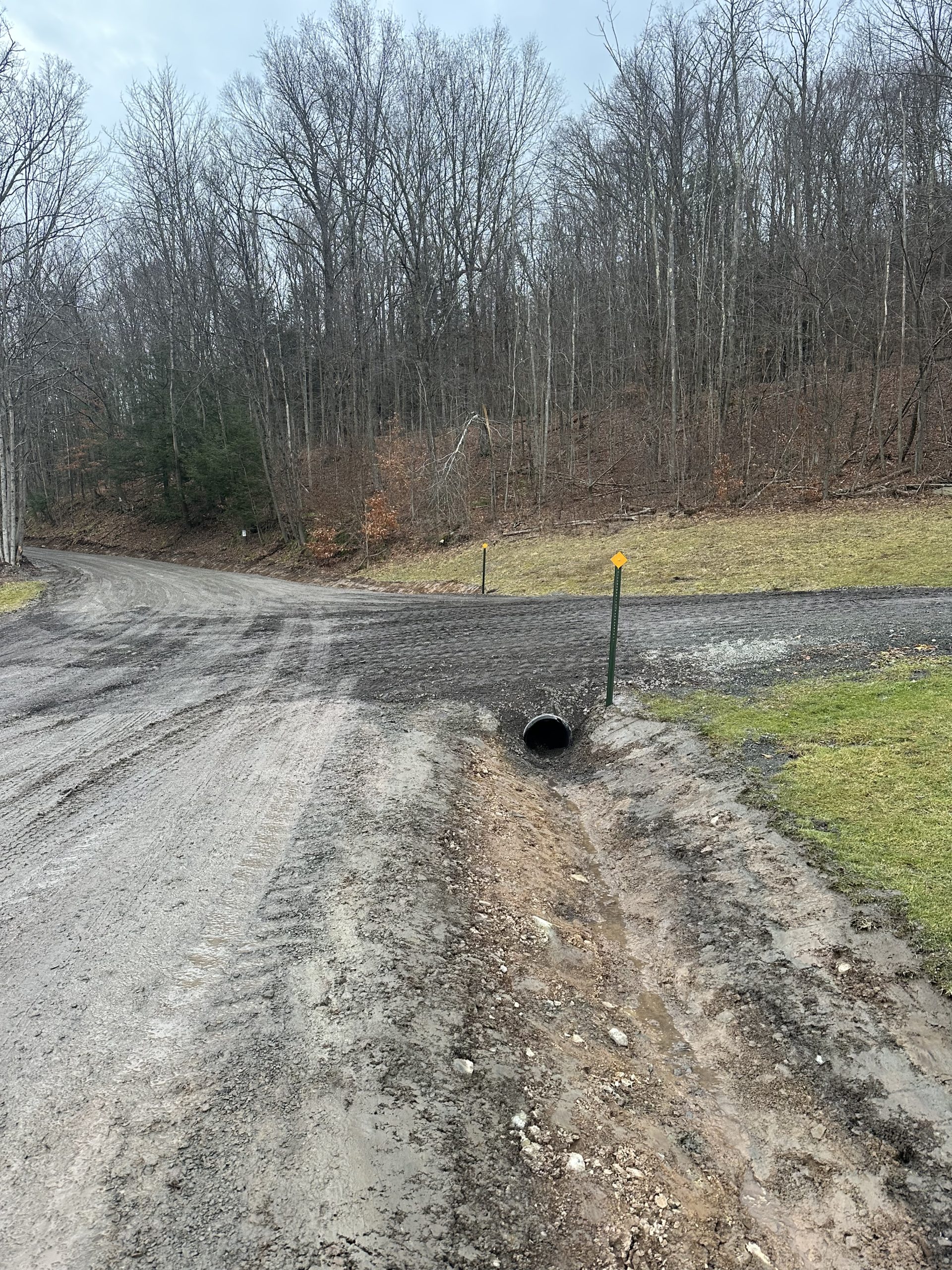 Dirt road intersection with drainage pipe.