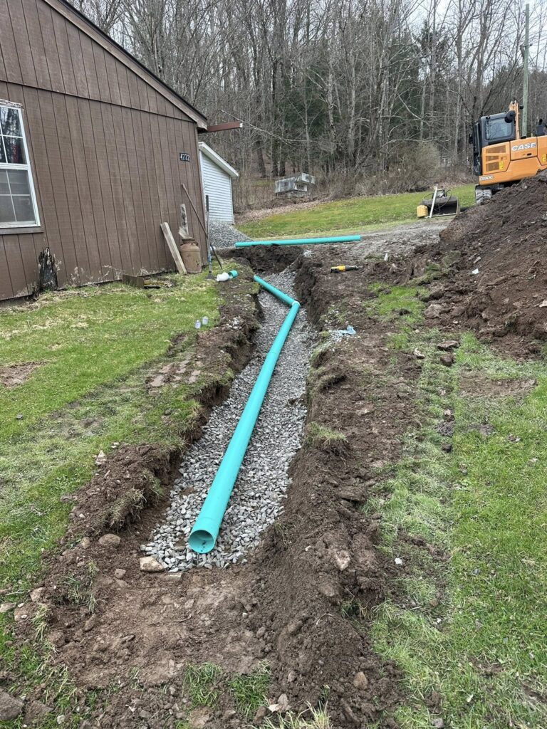 Trench with blue drainage pipe installed